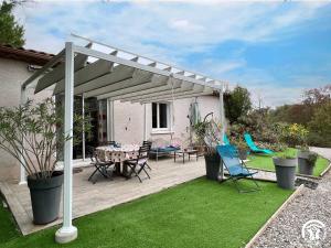 a pergola with a table and chairs on a deck at Le gite du pech de saint jean in La Redorte