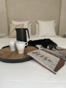 a tray with two cups and a book on a bed at Riad Manoury Marrakech - privates Boutique-Hotel für 6 in Marrakesh