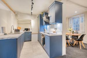 a large kitchen with blue cabinets and a table at Gatehouse Cottage in Cartmel in Rossendale