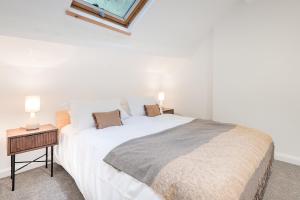 a bedroom with a large white bed and a night stand at Gatehouse Cottage in Cartmel in Rossendale