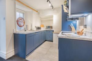 a large kitchen with blue cabinets and a window at Gatehouse Cottage in Cartmel in Rossendale +19 photos