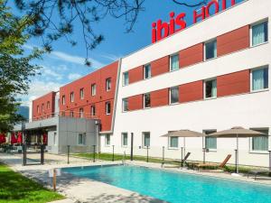 a hotel with a swimming pool in front of a building at Ibis Saint-Genis-Pouilly Genève in Saint-Genis-Pouilly