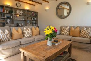 un salon avec un canapé et une table avec des fleurs dans l'établissement Luxury Skye Cottage Hot Tub & BBQ Lodge, à Lonmore