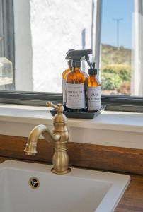 un lavabo avec deux bouteilles de savon sur le rebord d'une fenêtre dans l'établissement Luxury Skye Cottage Hot Tub & BBQ Lodge, à Lonmore 61 autres photos