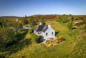 - une vue aérienne sur une maison blanche sur une colline dans l'établissement Luxury Skye Cottage Hot Tub & BBQ Lodge, à Lonmore