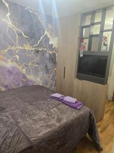 a bedroom with a bed with purple sheets and a tv at AKI lux apartman in Čačak