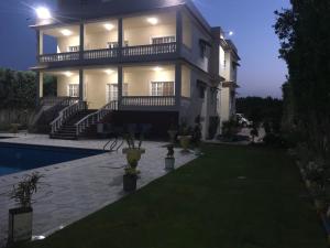 a large house with a swimming pool in front of it at Allam's Villa - Families only in Borg el Arab