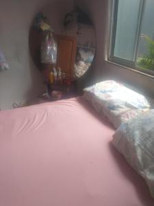 een slaapkamer met een roze bed en een spiegel bij Quartos para alugar na cop 30 in Ananindeua