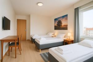 a room with three beds and a table and a desk at Hotelli Vilho in Kotka