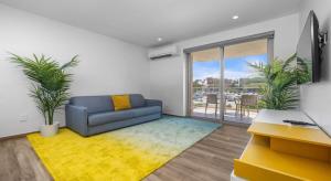een woonkamer met een blauwe bank en een geel tapijt bij Luxury 2BR Condo w/Pool, Rooftop, GYM @ Palm Beach in Palm-Eagle Beach