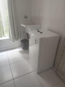 ein weißes Badezimmer mit einem Waschbecken und einem Kühlschrank in der Unterkunft Suíte Pé na areia in Santa Cruz Cabrália