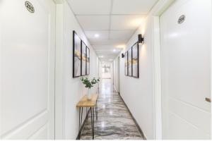 a hallway with white walls and a table with a plant on it at FabHotel Oakwey Inn - Indiranagar in Bengaluru