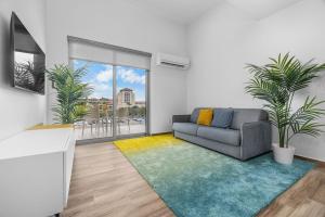 een woonkamer met een bank en wat planten bij 2BR2BA Condo w/ Pool & Gym – Walk to Palm Beach! in Palm-Eagle Beach