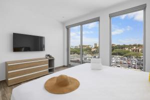 een witte slaapkamer met een groot bed met een hoed erop bij Modern 2BA2BR Condo Pool + Gym Near Palm Beach in Palm-Eagle Beach +26 foto's