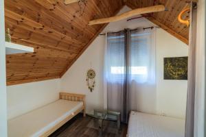 a room with two beds and a wooden ceiling at Non stop apartman in Kaposvár