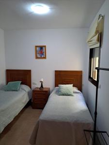 a bedroom with two beds and a lamp on a night stand at Apartamentos Plaza in Nerja +53 photos