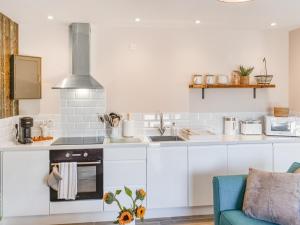 a kitchen with white cabinets and a blue couch at Elm - Uk50463 in Alvington
