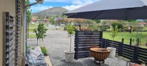 een patio met potplanten en een parasol bij Meadow View Guest Cottage in Wakkerstroom +8 foto's