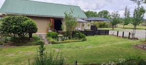 een huis met een groen dak en een tuin bij Meadow View Guest Cottage in Wakkerstroom