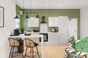 una cucina con armadi bianchi e 2 sgabelli da bar di New! 2BR in Gladstone a Hartlepool