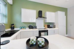 una cucina con armadi bianchi e pareti verdi di New! 2BR in Gladstone a Hartlepool Altre 33 foto