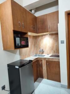 a kitchen with wooden cabinets and a black refrigerator at Best Eastern Apartment in Dhaka