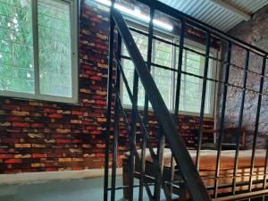 Una pared de ladrillo con ventanas y una escalera en una habitación en Leela villa - Ancient Redstone Escape, en Panchgani