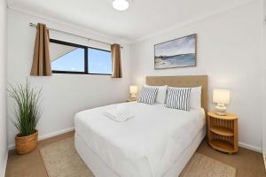 een slaapkamer met een groot wit bed en een raam bij Beachfront Bliss - At the Heart of It ALL in Townsville