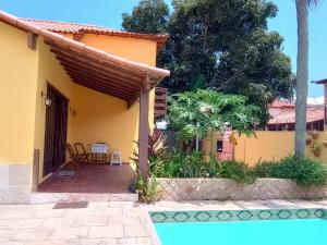 une maison jaune avec une piscine devant dans l'établissement Casa independente com piscina emCabo Frio RJ, à Cabo Frio