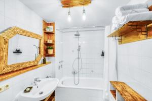 a bathroom with a white tub and a sink and a mirror at Apartment Bavaria - Zentral mit Stellplatz, Küche & Netflix in Pfaffenhofen an der Ilm +34 photos