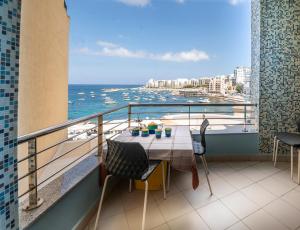 a balcony with a table with a view of the ocean at Modern SeaView Luxury Apartment in St. Paul's Bay