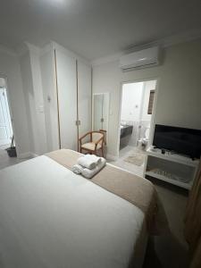 a white bedroom with a bed and a flat screen tv at Keurbooms River in Keurboomstrand +18 photos