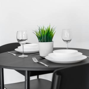 a black table with plates and glasses and a plant at Cozy Apartment - On street parking - Rowley Regis 49AG in Halesowen