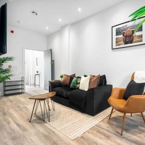 a living room with a black couch and a table at Cozy Apartment - On street parking - Rowley Regis 49AG in Halesowen