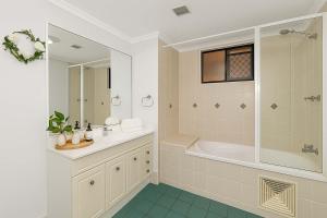 een witte badkamer met een bad en een wastafel bij Beachfront Bliss - At the Heart of It ALL in Townsville