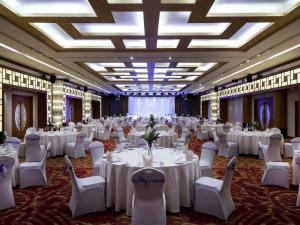 Un salón de banquetes con mesas y sillas blancas. en Pullman Zhangjiajie Hotel - Instagrammable, en Zhangjiajie