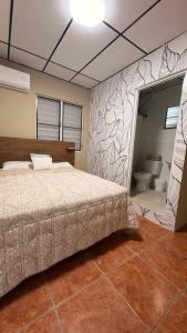 a bedroom with a bed and a bathroom with a toilet at Cozy Jayuya Apartment with City, Garden, and Mountain Views in Jayuya