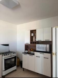 アハイアウ・ド・カボにあるIRIS Pousada - Frente à praiaのキッチン(白いキャビネット、コンロ、電子レンジ付)