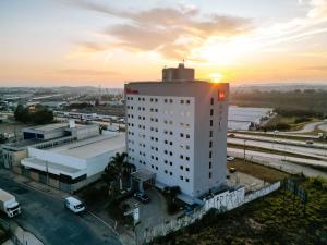 ein hohes weißes Gebäude mit Sonnenuntergang im Hintergrund in der Unterkunft ibis Contagem Ceasa in Contagem
