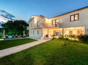 een groot wit huis met een groene tuin bij Villa Mima Pool Retreat in Opanci