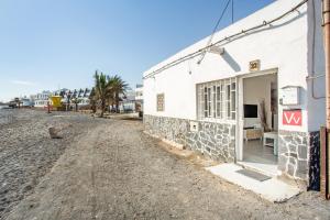 ein weißes Gebäude am Rande einer unbefestigten Straße in der Unterkunft La Casita De La Playa in Puerto de las Lajas