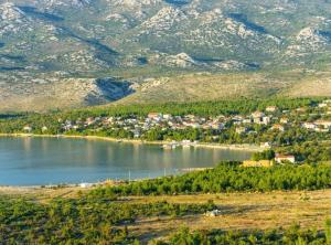 a town on the shore of a lake with mountains at Holiday Home Green Oasis Lika in Lovinac
