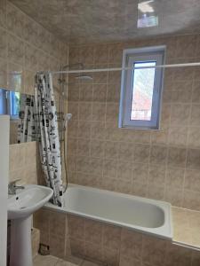 ein Badezimmer mit Badewanne und Waschbecken und einem Fenster in der Unterkunft Apartamenty EverySky Karkonoska 54/7 in Bierutowice