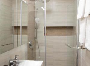 een badkamer met een douche, een wastafel en een glazen douchedeur bij Ginko Rooms in Daruvar