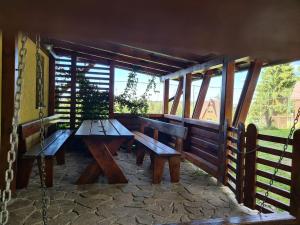 two benches on a porch with a fence at Zori de Zi & Apus de Soare in Bălceşti