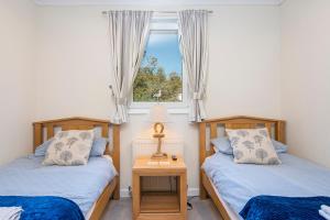 two twin beds in a room with a window at Pebble Reach in Amroth
