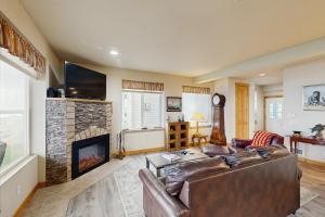 a living room with a leather couch and a fireplace at Ocean Lover's Landing in Gold Beach