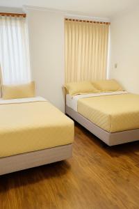 two beds in a room with wood floors at San Diego Suites Confort, Vista & Estacionamiento en Cuenca in Cuenca