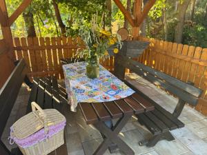 a wooden bench with a table with a vase of flowers at Malá jurta na Souvrati in Mostek +5 photos