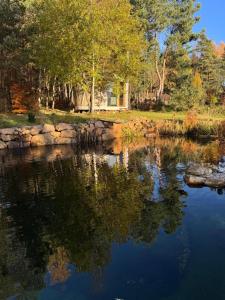 a body of water with a house in the background at Malá jurta na Souvrati in Mostek